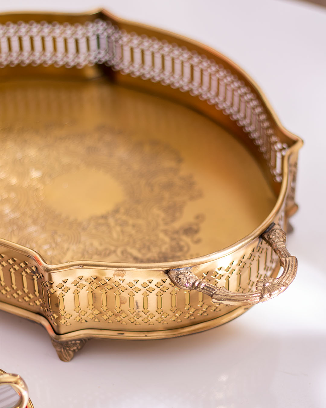 Close-up of gold tray handle with delicate lace cut-out detailing, showcasing exquisite craftsmanship for home decor.