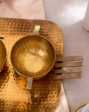 Detail-focused image of a hammered brass tray set with unique handle and decorative serving bowls , highlighting the luxury home accessories.